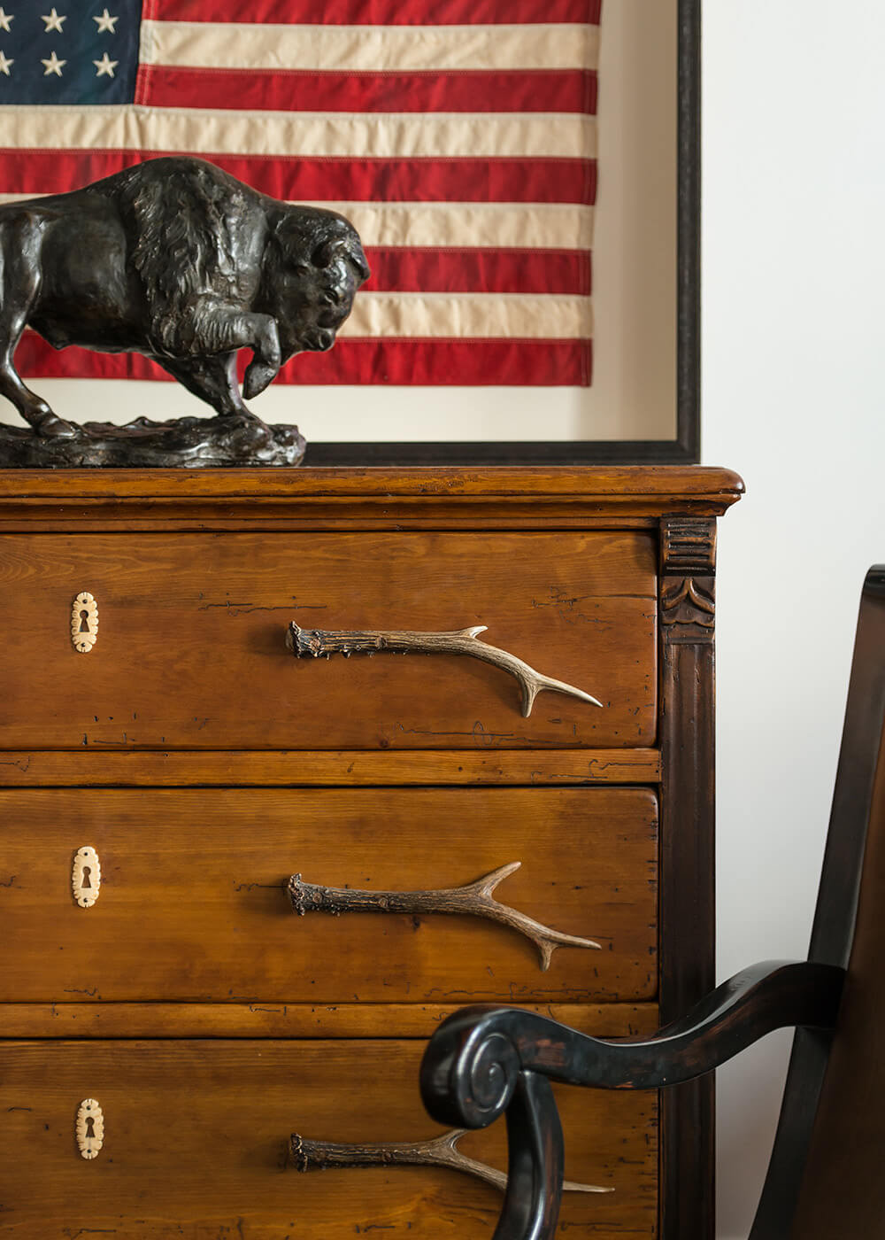 Framed American flag on dresser with buffalo statue.