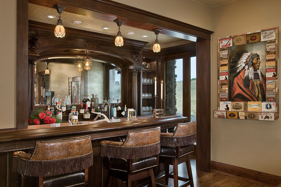 In home bar with liquer shelf in front of mirror, leather fringe barstools, a painting of Native American in a feather headdress
