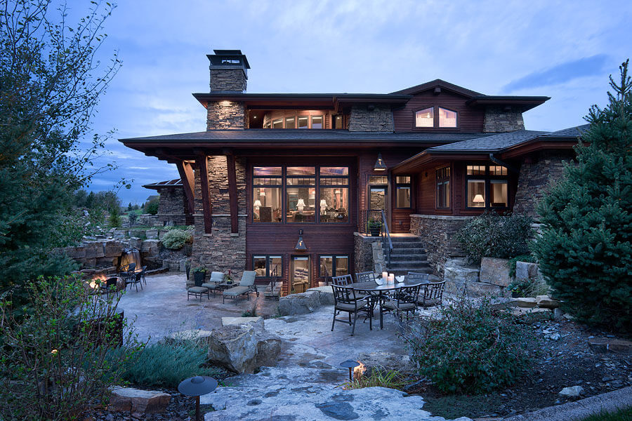 Stone patio at back of home with outdoor dining table, fire pit, and lounge chairs.