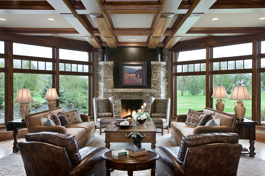 Living room with two leather arm chairs, two brown sofas, two side chairs, fireplace, view of green lawn out large front windows
