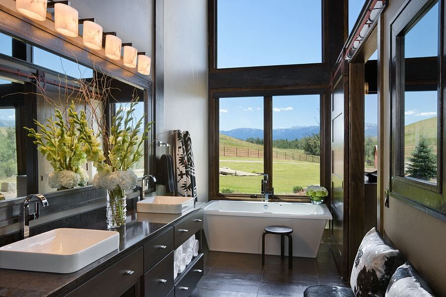 Master bath with double sink vanity, large bathtub, and view of countryside.