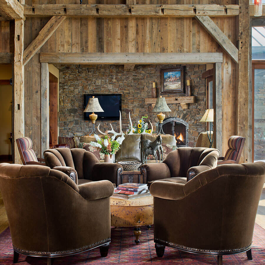 Living room with 4 brown mohair armchairs, cow hide ottoman, reclaimed wood walls and beams